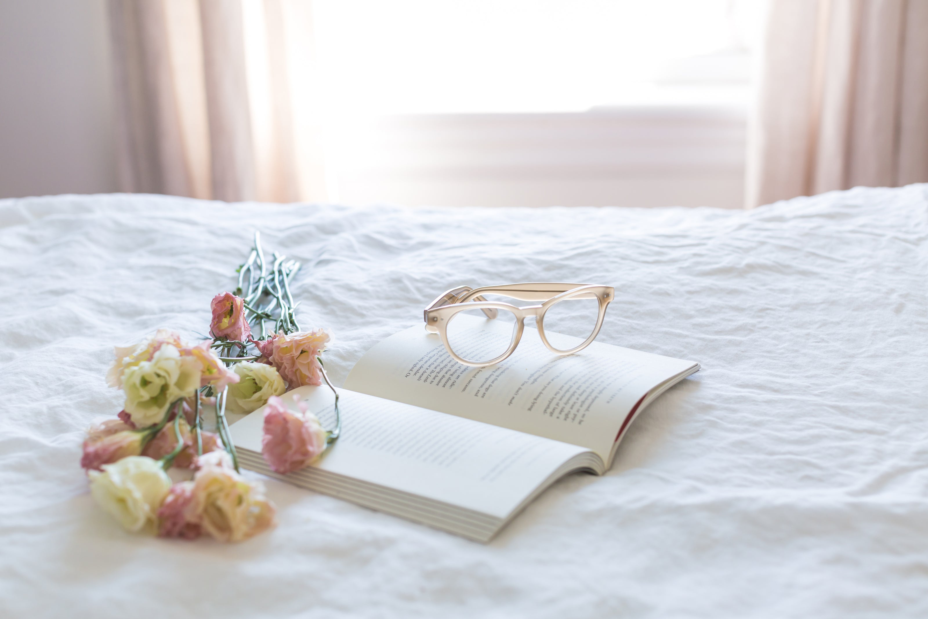 Book, Flowers, and Reading Glasses on a Bed